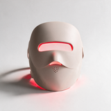 GlowTek Pro 4-in-1 LED mask, powered on with glowing red light, white studio background